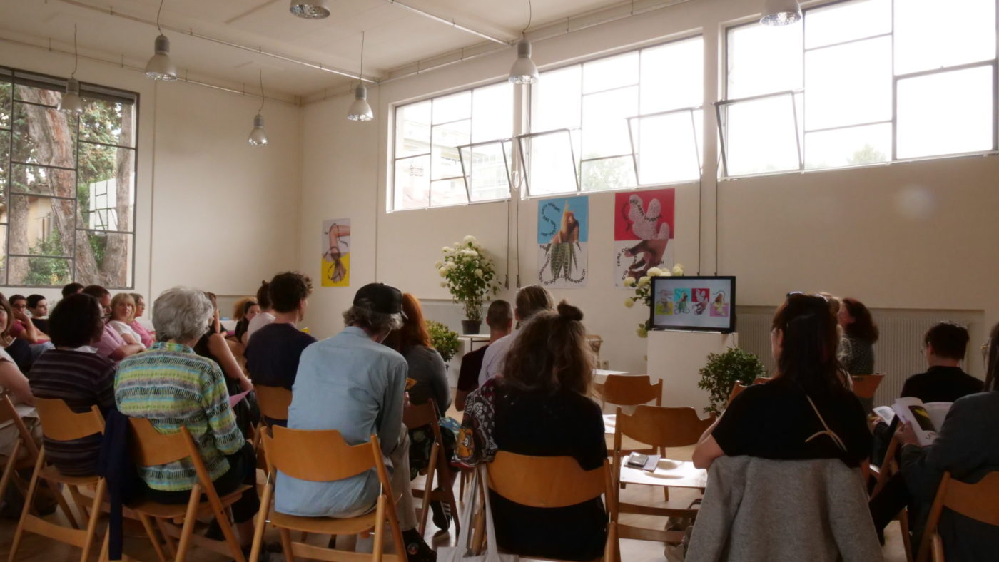 L'espace des Marchandises est rempli de chaises avec pas mal de personnes. L'espace accueil aussi les publics pour la révélation du programme, ce qui est le cas ici.
