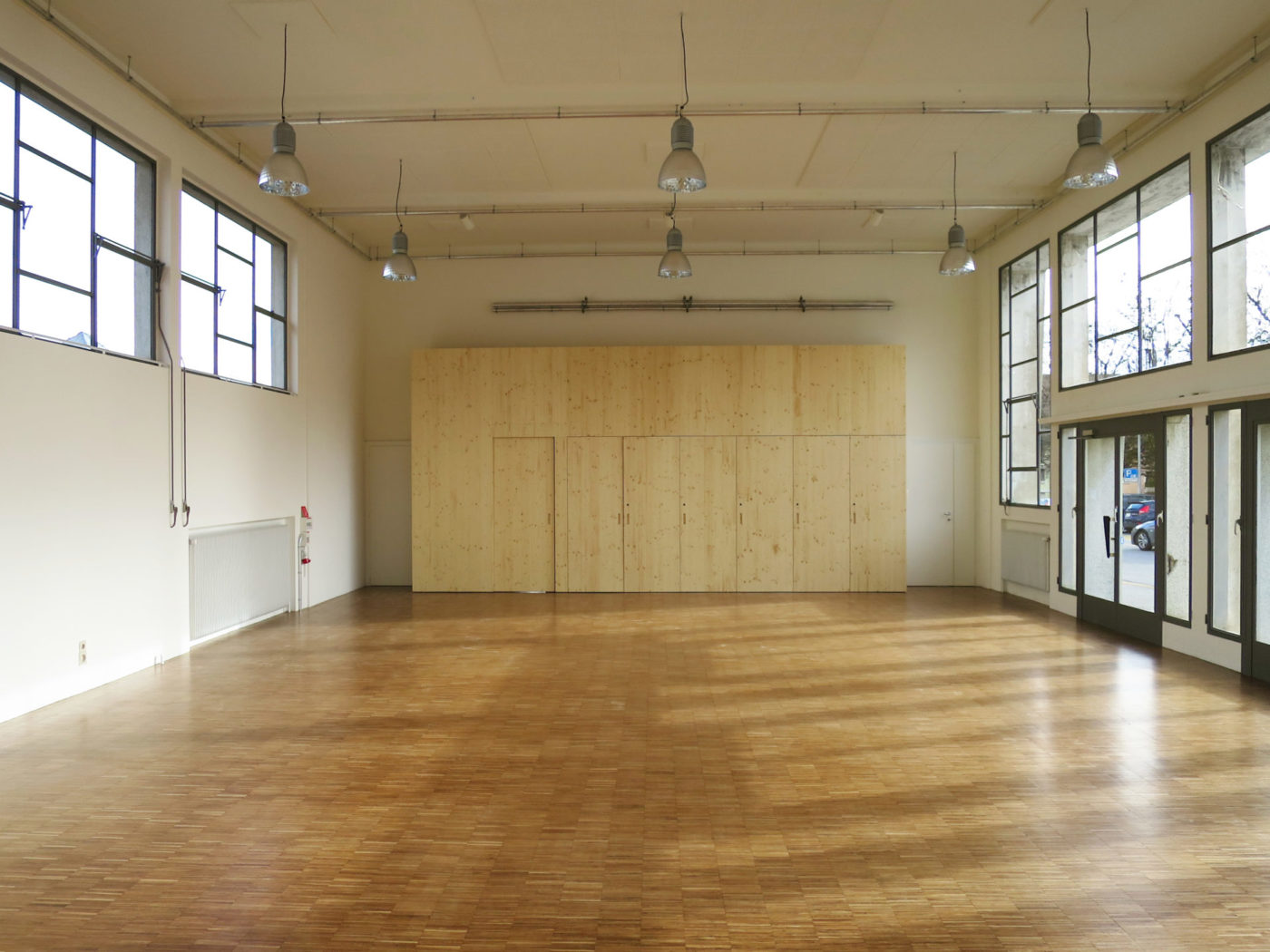 Voici l'intérieur de la salle des Marchandises. L'espace est lumineux avec ses nombreuses fenêtres et il y a une grande armoire en bois du côté du bureau du far°.